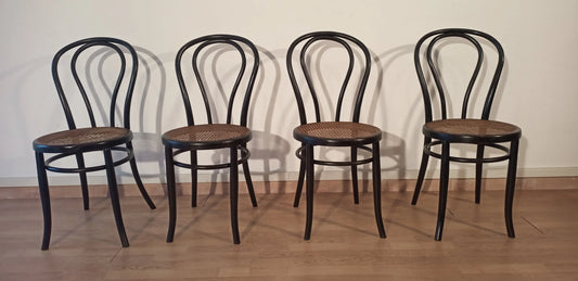 Vier zwarte, gebogen beukenhouten eetkamerstoelen uit de Thonet Italia-stijl, op een rij opgesteld.