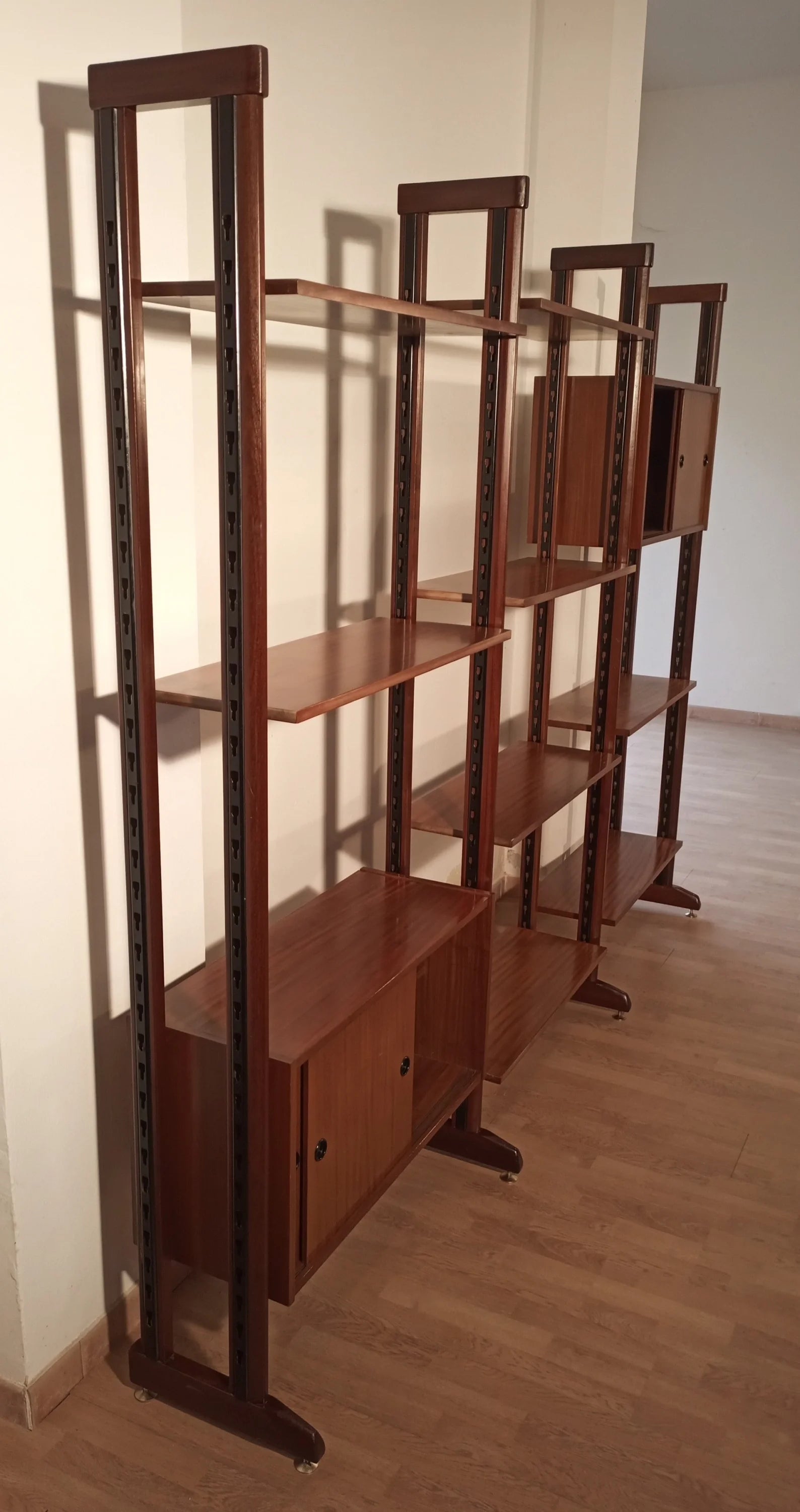 Moderna libreria vintage modulare in teak con supporti verticali e livelli espositivi multipli anni 60 Italia