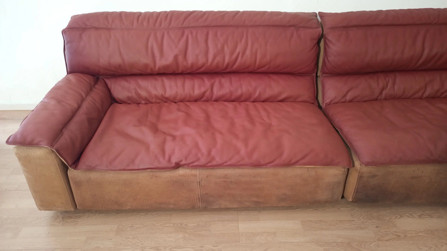Divano due tonalità con cuscini rossi e base color cuoio in pelle e pelle scamosciata vintage di carlo bartoli