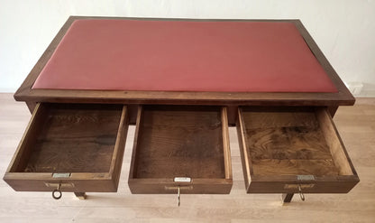 Scrivania stile impero in noce con piano in pelle rossa e tre cassetti aperti con piedini in ottone