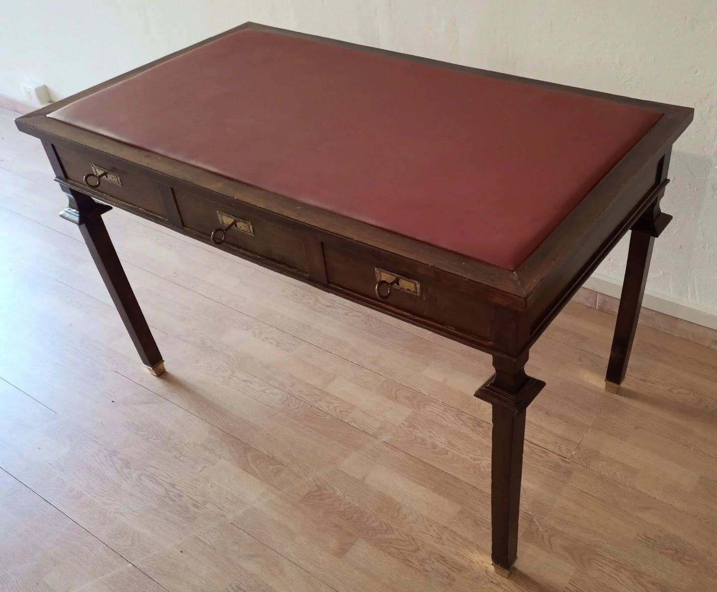 Scrivania stile impero in noce con piano in pelle rossa e tre cassetti con piedini in ottone